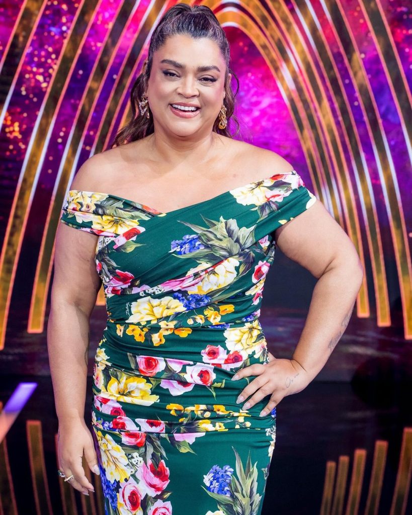 Imagem da cantora Preta Gil usando um vestido florido e com uma mão na cintura