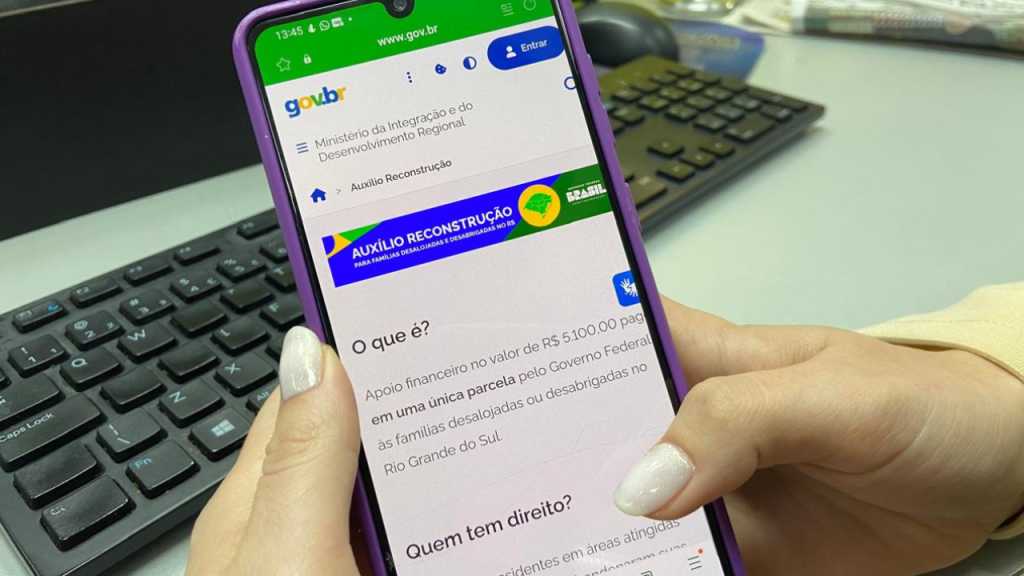 Celular aberto na página do Auxílio Reconstrução