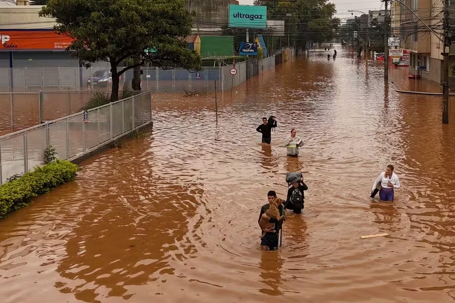 Pessoas tentam atravessar ruas alagadas no bairro Navegantes, em Porto Alegre